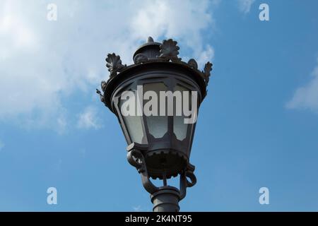 Straßenlaterne im Vintage-Stil, isoliert am blauen Himmel mit Wolken. Europäische Laterne im Retro-Stil Stockfoto