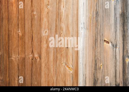 Holzstruktur mit vertikalen Linien. Die Textur von Holz mit Ästen und Löchern. Der Hintergrund besteht aus einem natürlichen Holzzaun. Roter Holzhintergrund. Stockfoto