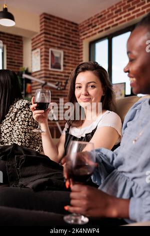 Junge Erwachsene kaukasische Frau Porträt Blick auf die Kamera, lächelnd, halten Weinglas, auf verschiedene Nationalitäten, Kulturen, Ethnien Freunde, Partner Wiedervereinigung, Treffen. Stockfoto