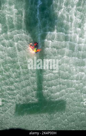 220926-N-EV253-1324 SAN DIEGO (SEPT. 26, 2022) – US Naval Aircrewman (Hubschrauber) 2. Klasse Devin Haswell, zugewiesen an Helicopter Sea Combat (HSC) Weapons School, Pacific, Und von East Greenwich, Rhode Island, sichert sich einen Übungsdummy an einen Wurf, bevor er ihn während einer dynamischen Proof of Concept-Übung in Glorietta Bay vor der Küste von Coronado, Kalifornien, am 26. September 2022 zu einem MH-60s Seahawk-Hubschrauber hochgezogen wird. Während der Entwicklung, die vom Chef der Marineoperationen (CNO) Search and Rescue Model Manager (SARMM) Komponente von HSC-3 überwacht wurde, wurde die Praktikabilität der Verwendung von zwei Rettungsschwimmern im Vergleich zu Stockfoto