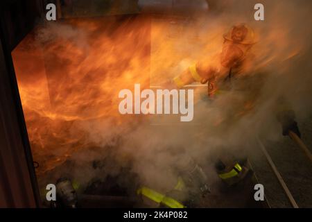 Ein Feuerwehrmann mit Camp Lejeune Fire and Emergency Services Division (FESD) beaufsichtigt die Feuerwehrleute, die sich während einer Live-Feuerübung im FESD-Schulungszentrum auf der Marine Corps Base (MCB) Camp Lejeune, North Carolina, am 27. September 2022 auf die Bekämpfung eines Überschlags vorbereiten. Das MCB Camp Lejeune FESD nahm im Oktober an verschiedenen Brandschutzaktivitäten Teil, um die National Fire Prevention Week 2022 zu fördern. Das diesjährige Thema lautet „Feuer wird nicht warten, planen Sie Ihre Flucht“. (USA Marine Corps Foto Lance CPL. Antonino Mazzamuto) Stockfoto