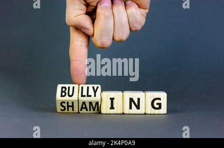 Symbol für Scham und Mobbing. Konzeptworte Shaming and Mobbing auf Holzwürfeln. Geschäftsmann Hand. Schöne graue Tabelle grauen Hintergrund. Geschäftsvorgetäuscht Stockfoto