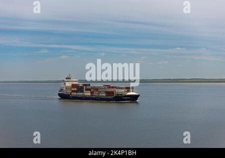 Brunsbuttel, Deutschland - 12. Juli 2022: Kieler Kanal, Nordsee. Voll beladenes Sonderborg-Containerschiff links Kanaleingang unter blauem Himmel Stockfoto