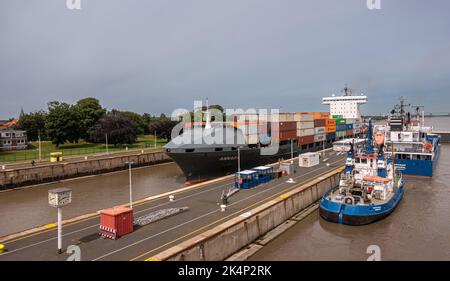 Brunsbuttel, Deutschland - 12. Juli 2022: Kieler Kanal, Nordseeseite. 3 Schiffe in den Schleusen unter dem verdichtenden grauen Himmel Stockfoto