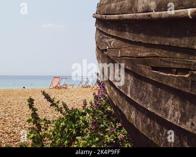 Verwitterte Planken eines alten Holzbootes verrotten im Vordergrund am Brighton Beach, Großbritannien Stockfoto