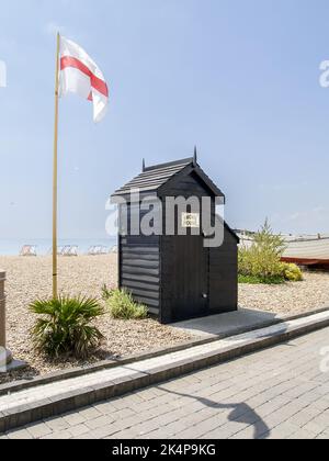 Brighton Beach Vereinigtes Königreich - Juni 16 2009; kleines dunkelbraunes Gebäude mit Rauchhaus an Türschild und Flagge Englands Stockfoto