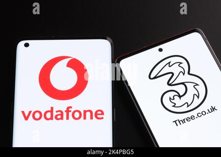 Vodafone und drei mögliche Fusionkonzepte. Die Smartphones werden zusammen mit den Logos der britischen Mobilfunkanbieter auf den Bildschirmen angezeigt. Stafford, Großbritannien, Oc Stockfoto