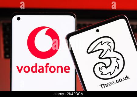 Vodafone und drei mögliche Fusionkonzepte. Die Smartphones werden zusammen mit den Logos der britischen Mobilfunkanbieter auf den Bildschirmen angezeigt. Stafford, Großbritannien, Oc Stockfoto