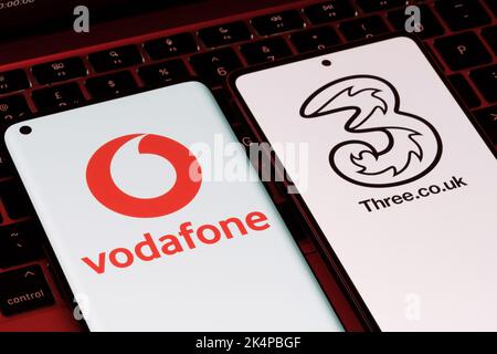 Vodafone und drei mögliche Fusionkonzepte. Die Smartphones werden zusammen mit den Logos der britischen Mobilfunkanbieter auf den Bildschirmen angezeigt. Stafford, Großbritannien, Oc Stockfoto