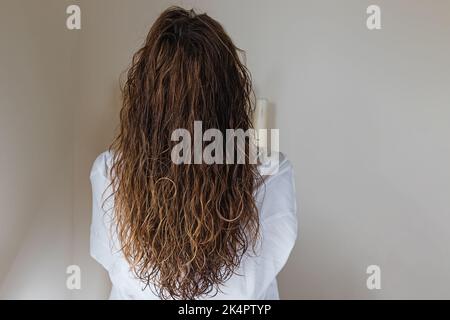 Brunette Frau mit langen welligen Haaren, Blick von hinten. Styling mit lockiger Methode Stockfoto
