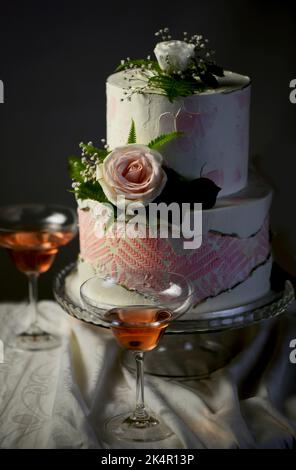 Hochzeitstorte mit frischen Blumen auf dunklem Hintergrund Stockfoto