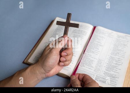 Hand hält religiöse Kruzifix Kreuz auf der Heiligen Bibel. Christlicher Glaube und Hingabe Konzept. Speicherplatz kopieren. Stockfoto