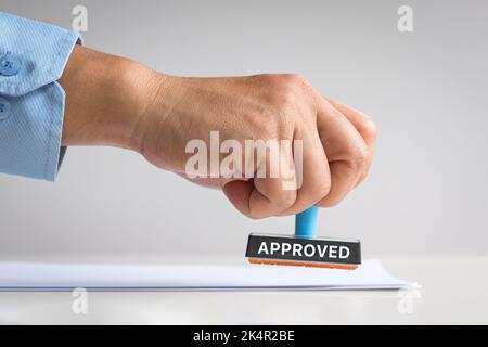 Genehmigter notarieller Stempel. Die Hand des Mannes drückt auf das Dokument. Stockfoto