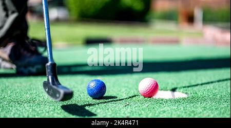 Minigolf-Spiel mit mehreren farbigen Kugeln in der Art eines Putter aufgereiht. Stockfoto