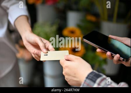 Eine asiatische Kundin, die ihre Sachen mit einer Kreditkarte bezahlt. Kreditkartenzahlungskonzept. Zugeschnittenes Bild Stockfoto