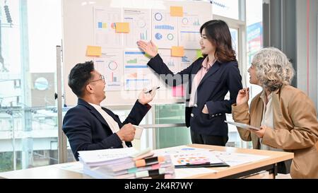 Eine professionelle, tausendjährige asiatische Geschäftsfrau oder Finanzanalytikerin berät ihren Geschäftskunden bei einer Finanzinvestition und präsentiert einen Finanzier Stockfoto