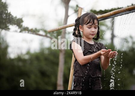 Kind Mädchen hat Spaß spielen im Wasser im Freien. Stockfoto