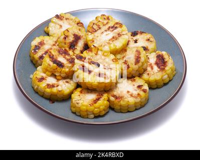 Gegrillte Maiskolben mit Streifen von einem Grill in Keramikplatte isoliert auf weißem Hintergrund Stockfoto