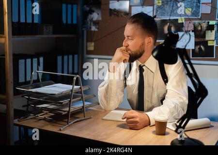 Detective arbeitet am Schreibtisch in seinem Büro, Ermittler analysiert Kriminalfall arbeiten in der Nacht während der Untersuchung Stockfoto