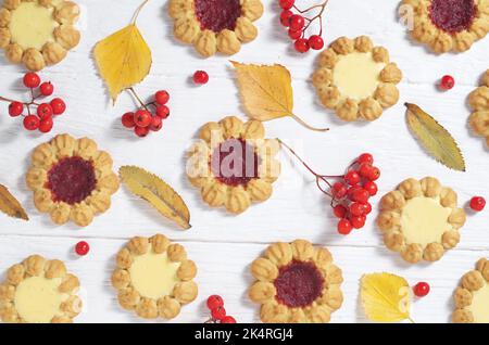 Verschiedene Arten von süßen Shortbread-Keksen, Herbstblättern und Beeren auf Holzhintergrund, Draufsicht Stockfoto