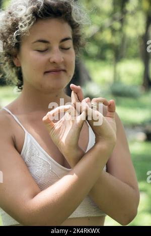 Kaukasische Frau in Sportbekleidung, die Yoga macht, stellt sich in der Natur. Yoga im Freien Stockfoto