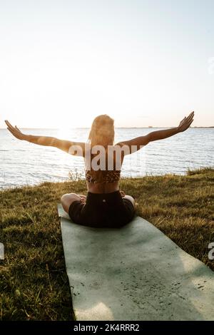 Kaukasische Frau in Sportbekleidung, die Yoga macht, stellt sich in der Natur. Yoga im Freien Stockfoto