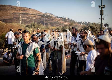 Nablus, Palästinensische Gebiete. 04. Oktober 2022. Israelische rechte Siedler beten, während sie den Haupteingang zur palästinensischen Stadt Nablus im nördlichen Westjordanland blockieren. Quelle: Ilia Yefimovich/dpa/Alamy Live News Stockfoto