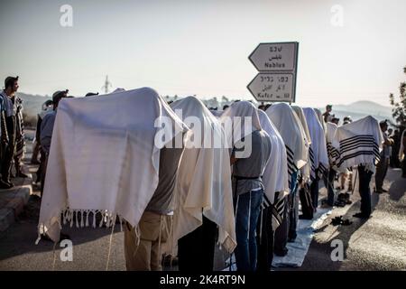 Nablus, Palästinensische Gebiete. 04. Oktober 2022. Israelische rechte Siedler beten, während sie den Haupteingang zur palästinensischen Stadt Nablus im nördlichen Westjordanland blockieren. Quelle: Ilia Yefimovich/dpa/Alamy Live News Stockfoto