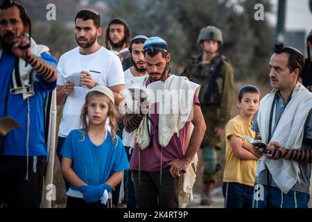 Nablus, Palästinensische Gebiete. 04. Oktober 2022. Israelische rechte Siedler beten, während sie den Haupteingang zur palästinensischen Stadt Nablus im nördlichen Westjordanland blockieren. Quelle: Ilia Yefimovich/dpa/Alamy Live News Stockfoto