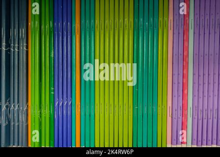 Bunte Notizbücher im Regal der Buchhandlung. Viele Bücher mit hellen Einbänden in einem Stapel. Designelement, Papier- und Lederstruktur. Stockfoto