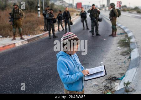 Nablus, Palästinensische Gebiete. 04. Oktober 2022. Ein israelisches Kind betet, während israelische rechte Siedler am Haupteingang der palästinensischen Stadt Nablus im nördlichen Westjordanland blockieren und beten. Quelle: Ilia Yefimovich/dpa/Alamy Live News Stockfoto