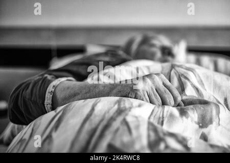 Faltige Hand einer alten Frau, die im Bett lag. Leitender Patient Stockfoto