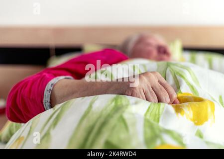Faltige Hand einer alten Frau, die im Bett lag. Leitender Patient Stockfoto
