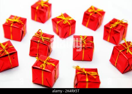 Schachteln in rotem Geschenkpapier mit Schleife auf weißem Hintergrund verpackt. Stockfoto
