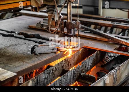 Sauerstoffbrenner schneidet Stahlblech. CNC-Gasschneidemaschine. Helle Funkenschutzfolie aus geschmolzenem Metall. Stockfoto