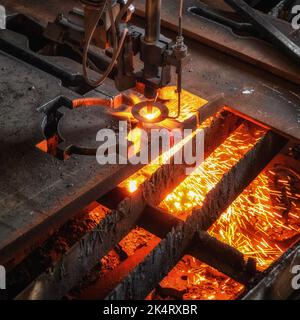 Sauerstoffbrenner schneidet Stahlblech. CNC-Gasschneidemaschine. Helle Funkenschutzfolie aus geschmolzenem Metall. Stockfoto