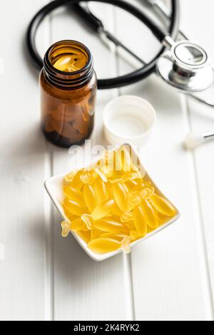 Fischöl-Kapseln. Gelbe Omega-3-Pillen in der Schüssel auf dem weißen Tisch. Stockfoto