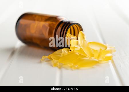 Fischöl-Kapseln. Gelbe Omega 3 Pillen in Glasflasche auf dem weißen Tisch. Stockfoto