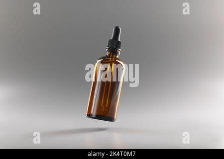 Braune Flasche mit Pipette auf grauem Hintergrund Stockfoto