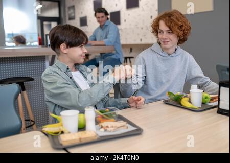 In der Kantine grüßen sich die Schüler gegenseitig Stockfoto