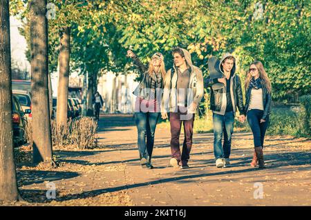 Gruppe von glücklichen besten Freunden mit alternativen Mode Blick zu Fuß im Park - Hipster Touristen Spaß im Freien an sonnigen Wintertag - Universität Stockfoto