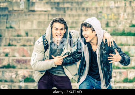 Junge Hipster-Brüder, die Spaß miteinander haben - die besten Freunde, die gemeinsam im Stadtgebiet im Freien Freizeit verbringen - hübsche Jungs mit Wintermode Stockfoto