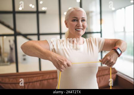 Fröhliche blonde Dame, die eine Oberkörperübung macht Stockfoto