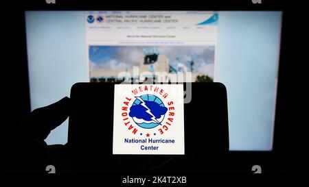 Person mit Mobiltelefon und Logo der US-amerikanischen NWS-Division National-Windsurecenter (NHC) auf dem Bildschirm vor der Webseite. Konzentrieren Sie sich auf die Telefonanzeige. Stockfoto
