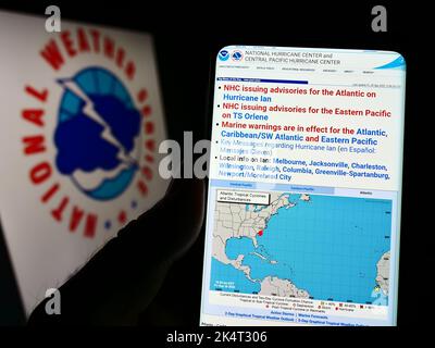 Person mit Smartphone und Website der US-amerikanischen NWS-Division National-Windsurmzentrum (NHC) auf dem Bildschirm mit Logo. Konzentrieren Sie sich auf die Mitte des Telefondisplays. Stockfoto