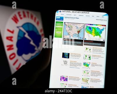 Person, die Mobiltelefon mit der Webseite der US-Agentur National Weather Service (NWS) auf dem Bildschirm vor dem Logo hält. Konzentrieren Sie sich auf die Mitte des Telefondisplays. Stockfoto