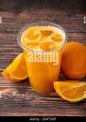 Frisch gepresster Orangensaft mit Eiswürfeln auf Holztisch Stockfoto