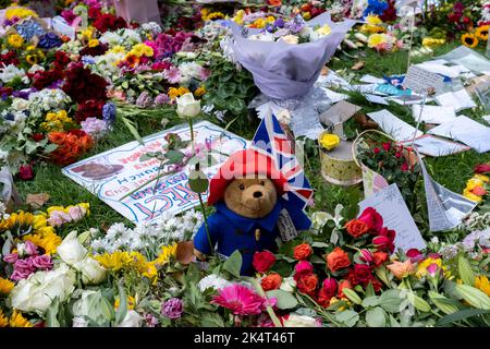 Nahaufnahme von Blumengedenken und einem Spielzeug Paddington Bear als Öffentlichkeit versammeln sich, um Blumen in einem temporären Gedenkgarten im Green Park nach dem Tod von Königin Elizabeth II und der Proklamation des neuen Königs Charles III am 11.. September 2022 in London, Großbritannien, zu legen. Ein Team von Freiwilligen und Mitarbeitern von Royal Parks entfernte Plastik aus den Bündeln. König Charles, der für seine Umweltarbeit bekannt ist, ist gegen Blumen, die in Plastik gewickelt sind. Stockfoto