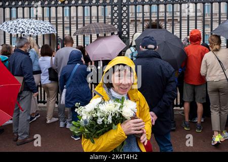 Die Öffentlichkeit ist unbeirrt von dem nassen Wetter, am Buckingham Palace vorbei in Richtung Green Park zu gehen, um nach dem Tod von Königin Elizabeth II. Blumen zu legen, und der Proklamation des neuen Königs Charles III. Am 13.. September 2022 in London, Großbritannien. Die Größe und das Volumen der Blumen, die als Denkmal für die Königin hinterlassen wurden, zeigen die Tiefe des Gefühls, das die Menschen für den verstorbenen Monarchen haben. Stockfoto