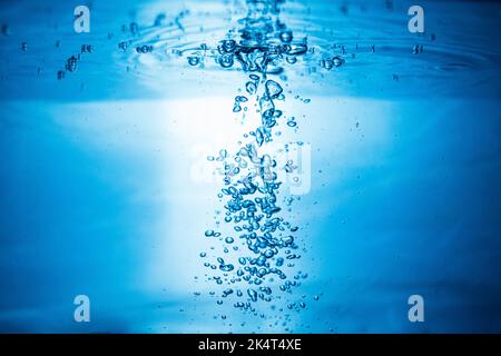 Ein abstrakter Hintergrund, der durch Luftblasen im Wasser unter blauem Licht entsteht. Stockfoto